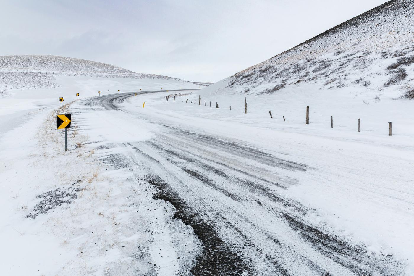 Icy road with bend warning sign — harsh cornering and braking risks for fleet drivers in winter conditions